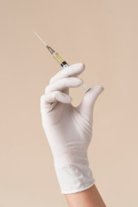 Hand with latex glove holding Juvederm syringe